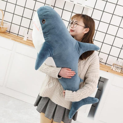 Girl looking a the face of a shark stuffed plushie