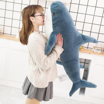 Girl kissing the fabric of a shark stuffed pillow toy