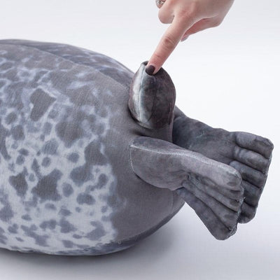 A back half of a fat seal plushie with its tail being pushed with index finger