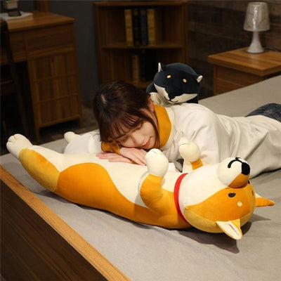 Woman laying on the stomach of a yellow shiba stuffie
