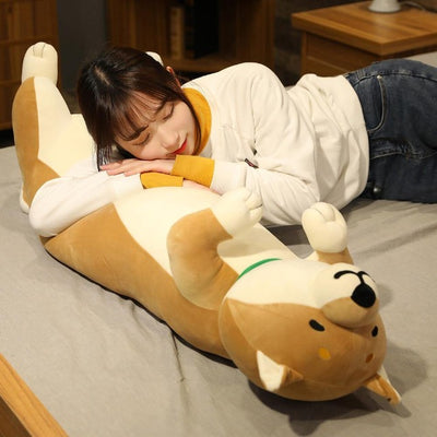 woman laying on a happy and smiling shiba stuffed animal