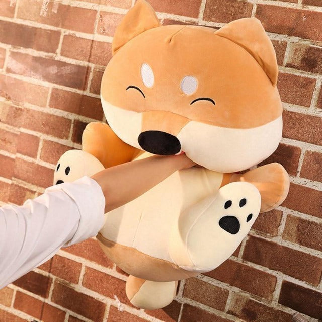 woman pushing on the face of a cartoon like shiba inu plush toy