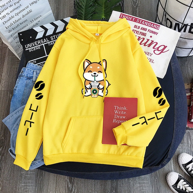 yellow hoodie with a shiba smiling drinking a drink through a straw